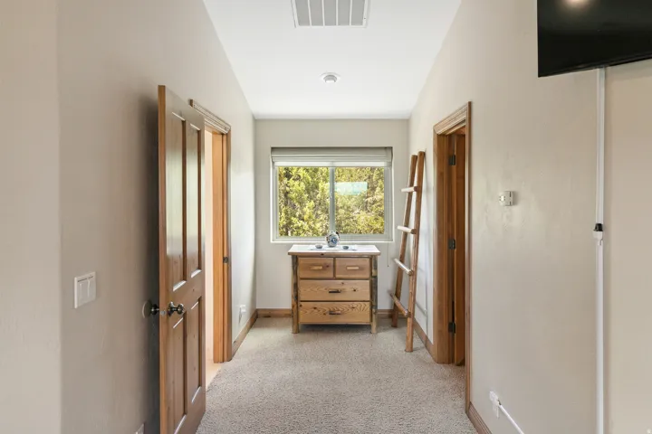 Hallway with light colored carpet and baseboards