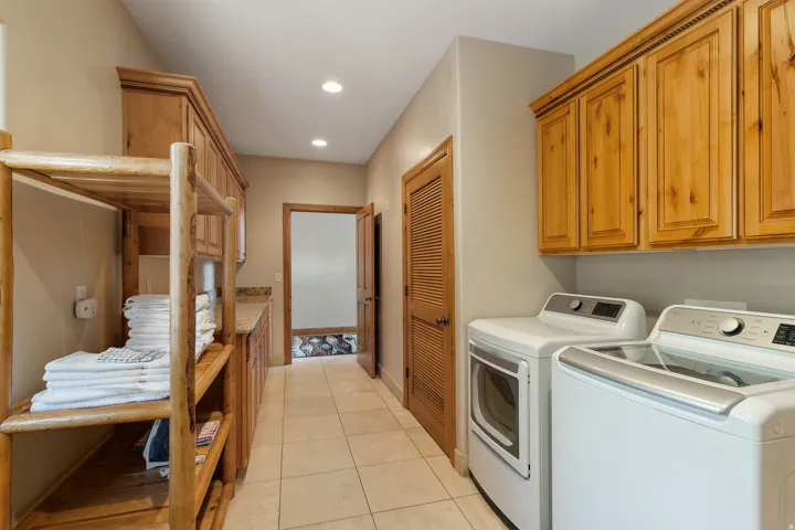Laundry room with light tile patterned flooring, washer and dryer, cabinet space, and recessed lighting