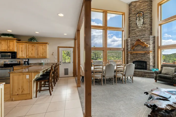 Kitchen featuring stainless steel appliances, a breakfast bar area, dark stone countertops, light colored carpet, and a fireplace