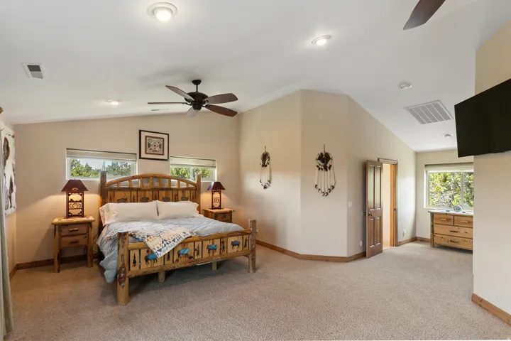 Bedroom with lofted ceiling, a ceiling fan, and light colored carpet
