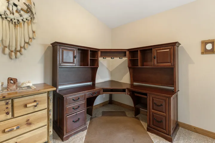 Office with vaulted ceiling, built in desk, and light carpet