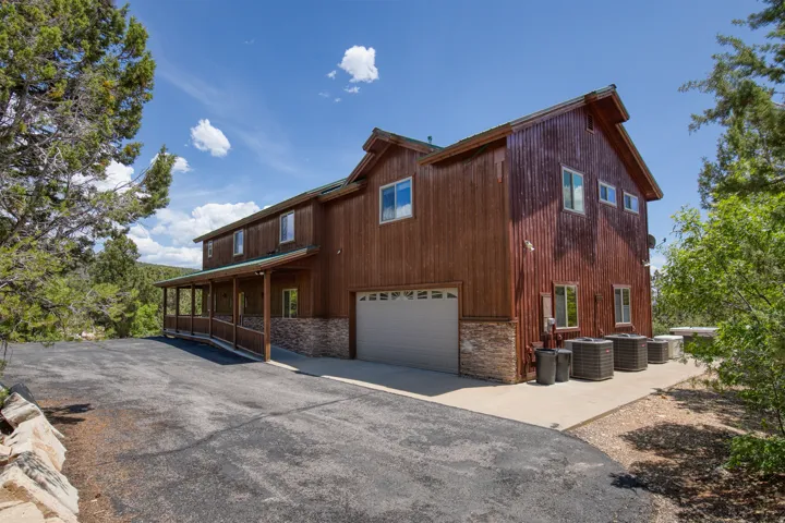 View of side of property with stone siding, asphalt driveway, and an attached garage