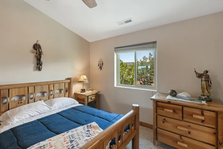 Bedroom with lofted ceiling, ceiling fan, and light carpet