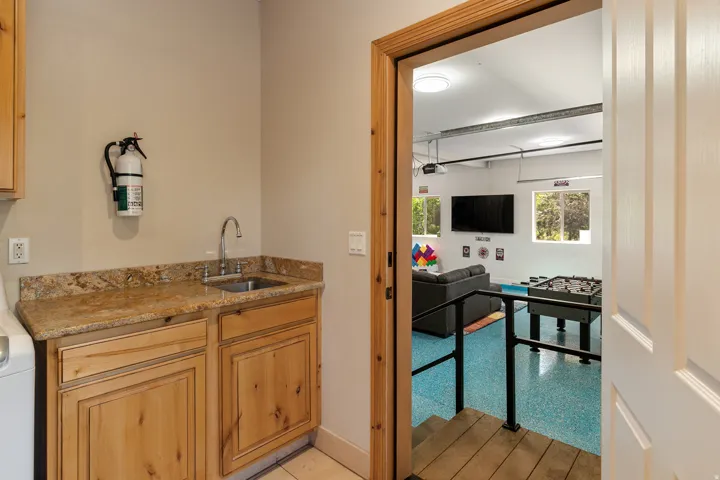 Bar with light stone counters, washer / clothes dryer, and light wood finish cabinetry
