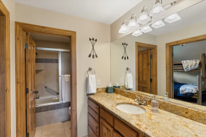 Ensuite bathroom featuring vanity, tiled shower / bath combo, and light tile patterned floors