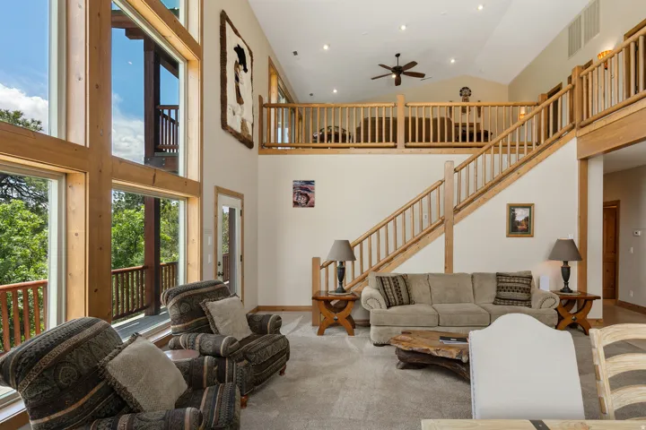 Carpeted living area with a ceiling fan, lofted ceiling, and recessed lighting