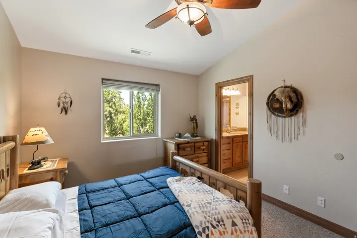 Bedroom featuring lofted ceiling, carpet flooring, connected bathroom, and ceiling fan