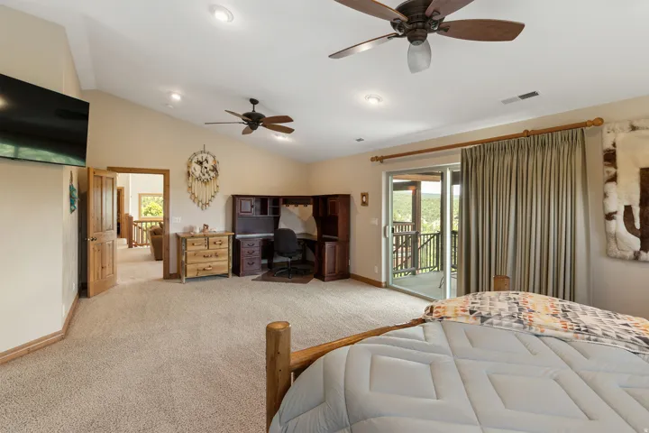 Bedroom with a ceiling fan, access to exterior, light colored carpet, vaulted ceiling, and an office area