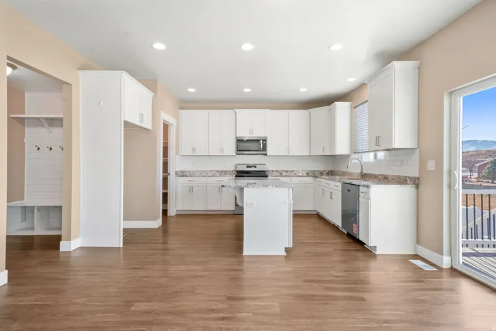 Kitchen with white cabinetry, a kitchen breakfast bar, dark wood-type flooring, a center island, and recessed lighting