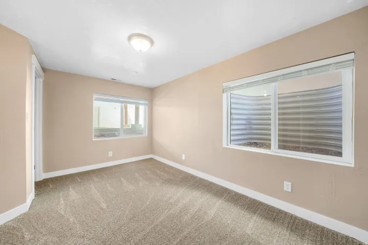 Basement secondary bedroom with light colored carpet and baseboards