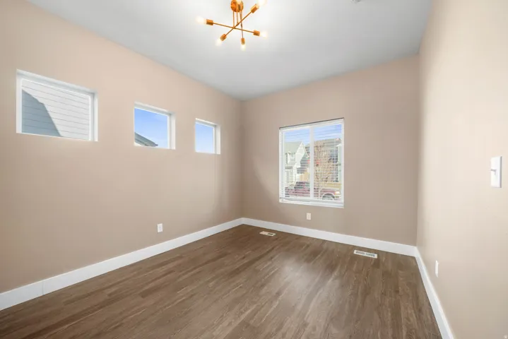 Spare room featuring modern chandelier lights and wood finished floors