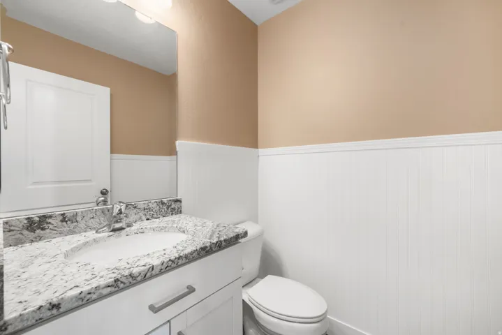 Guest half bath with granite counter vanity and wainscoting