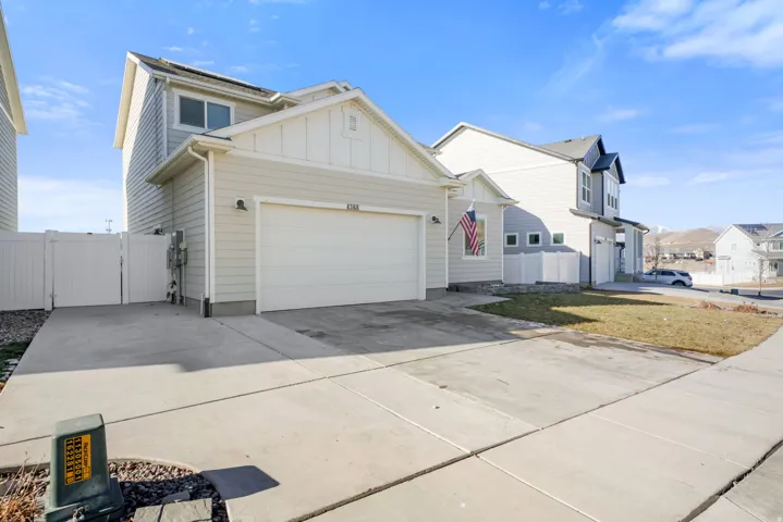 View of front of property featuring board and batten siding, a gate, extended concrete driveway, an attached garage, and a residential view