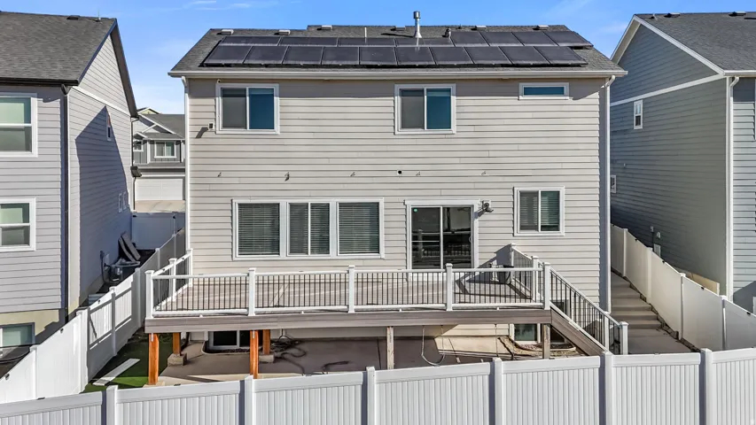 Back of house with a deck and solar panels