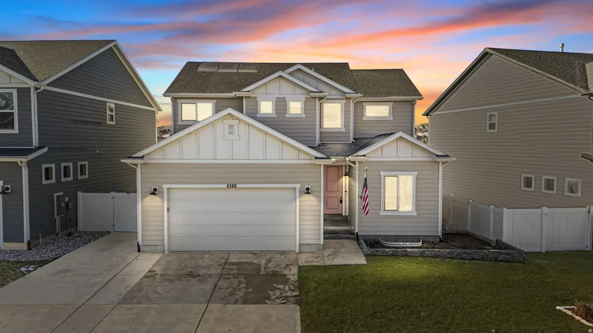 Evening View of front facade featuring board and batten siding, driveway, and a shingled roof