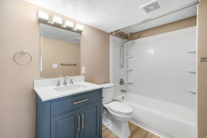 Full bathroom featuring vanity, tub / shower combination, light wood finished floors, and a textured ceiling