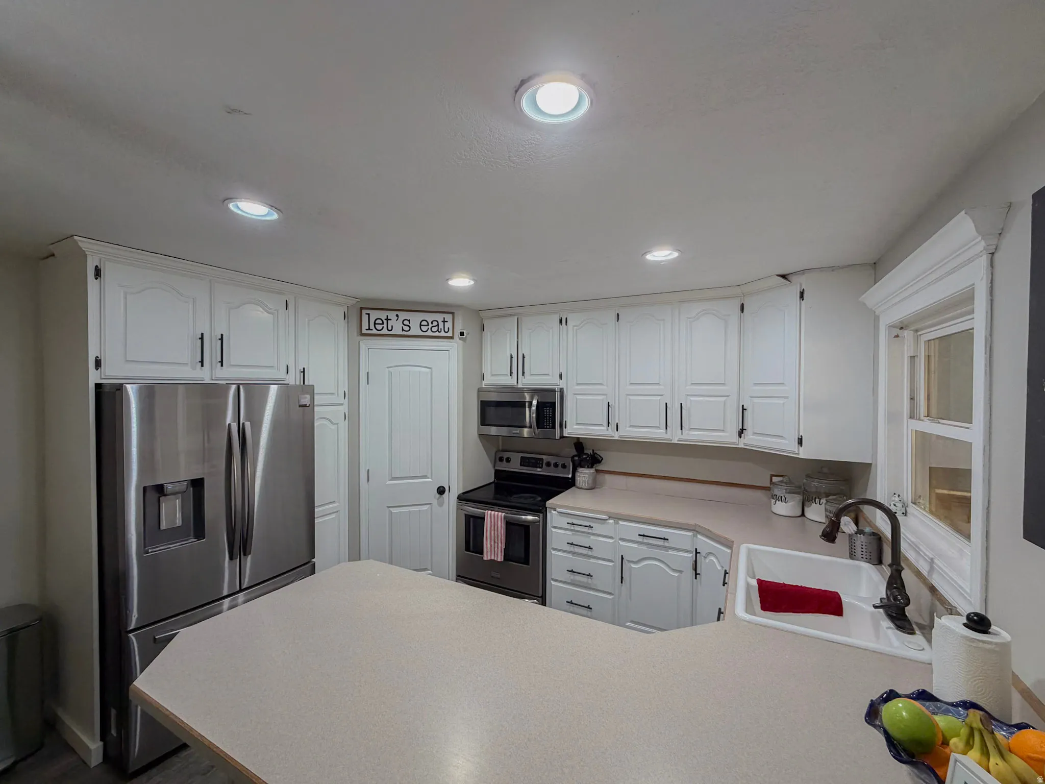 Kitchen featuring light countertops, stainless steel appliances, white cabinets, a peninsula, and recessed lighting