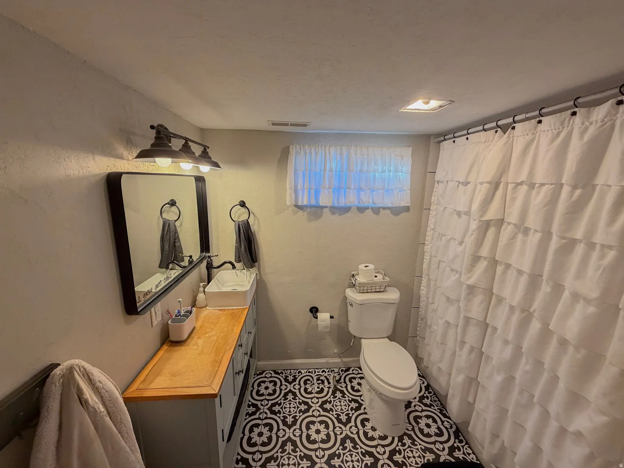 Bathroom featuring vanity, a shower with shower curtain, a textured ceiling, and tile patterned flooring