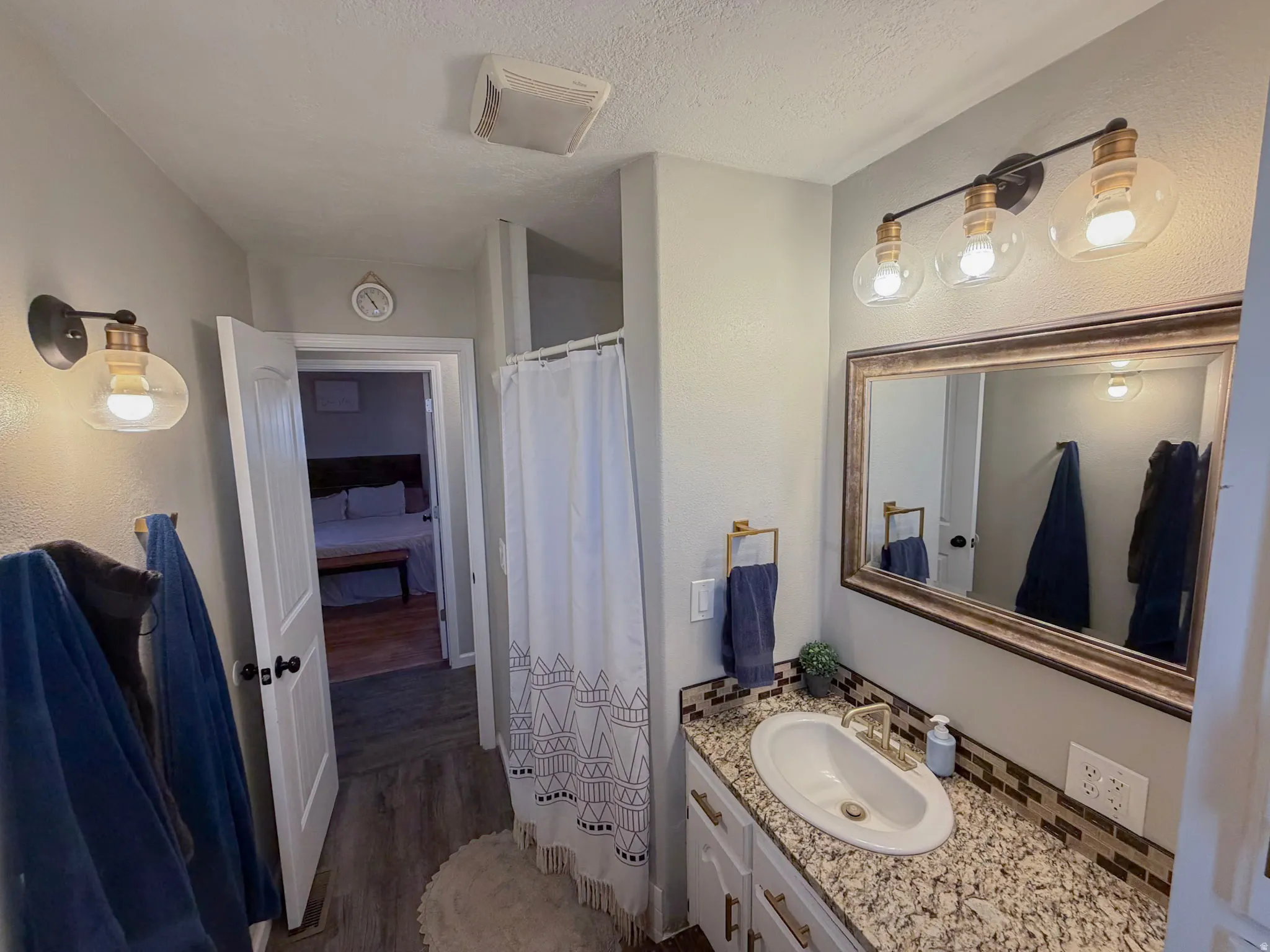 Ensuite bathroom with a shower with curtain, vanity, dark wood finished floors, and a textured ceiling