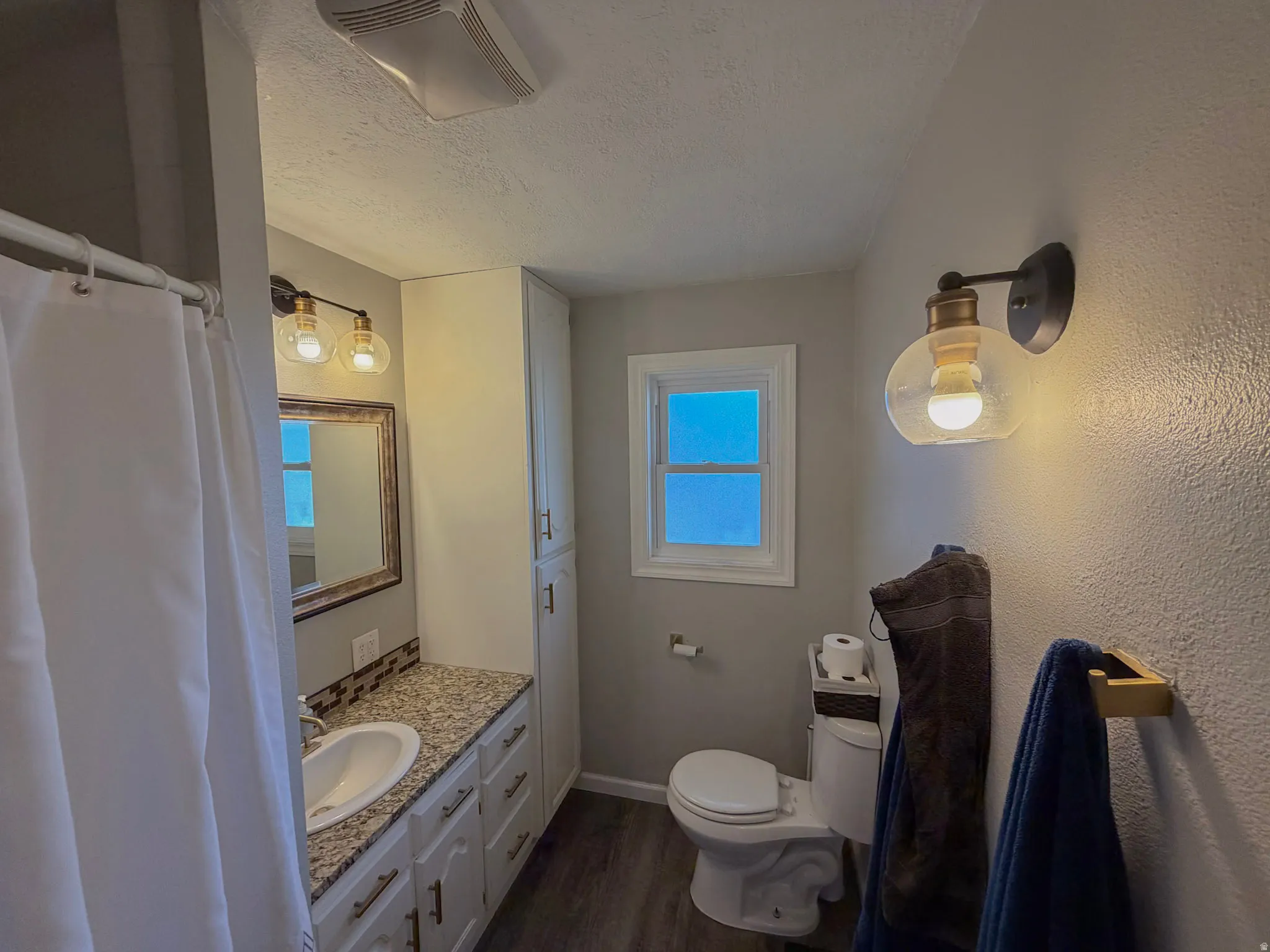 Bathroom with a textured ceiling, vanity, and dark wood finished floors