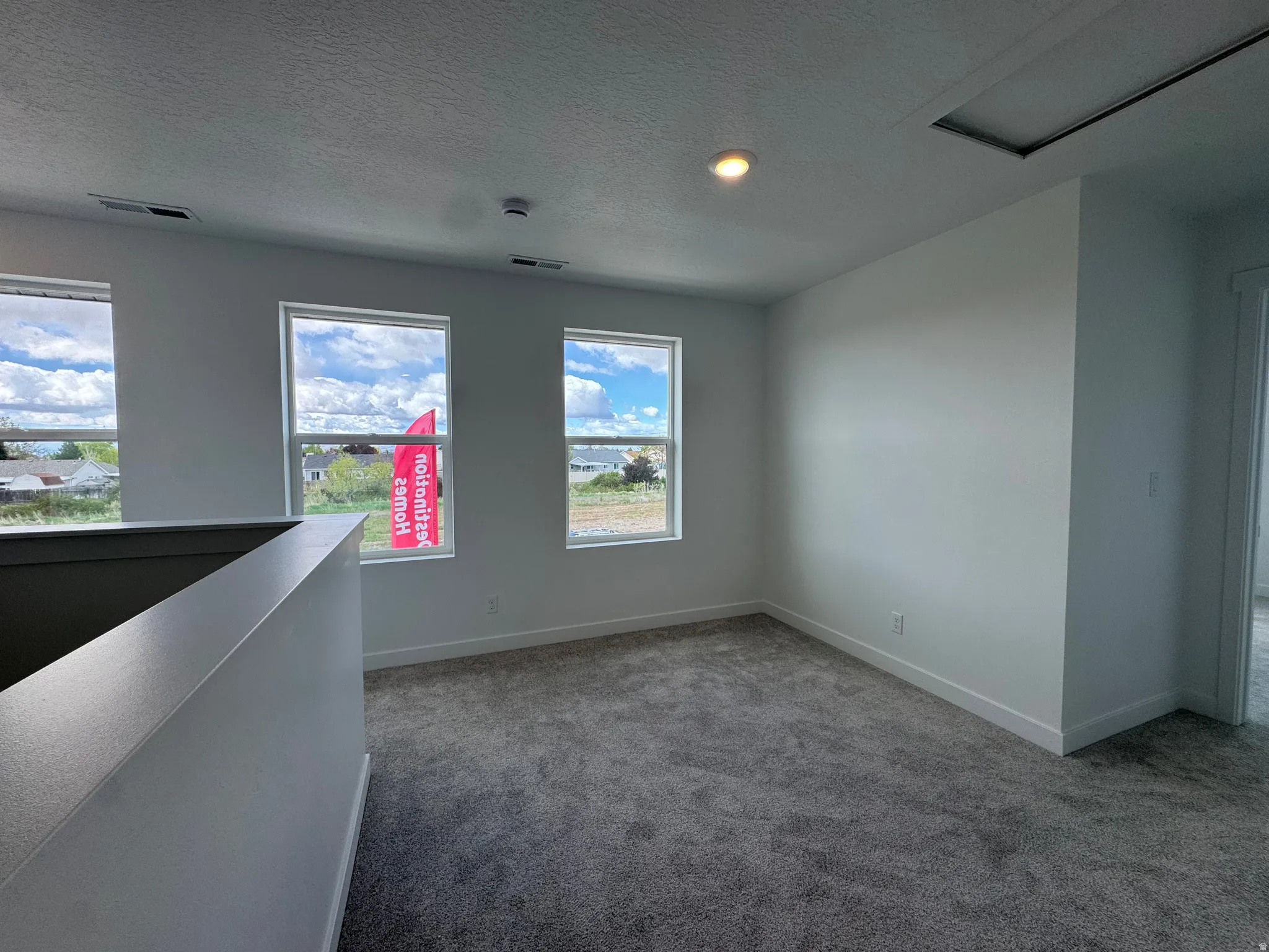Carpeted spare room featuring baseboards and a textured ceiling
