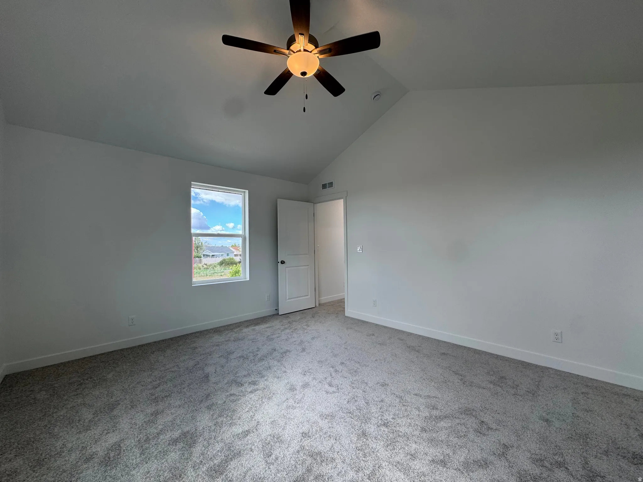 Unfurnished bedroom featuring carpet floors, ceiling fan, and a high ceiling