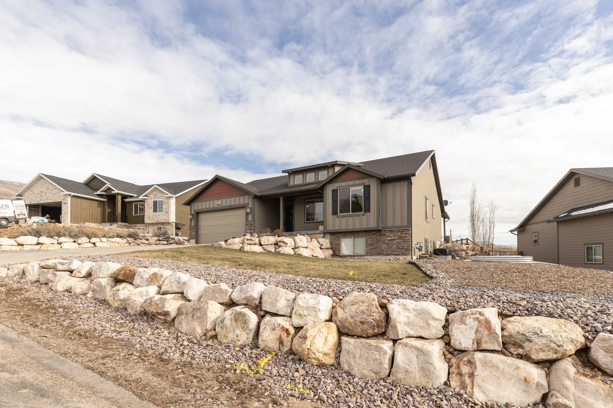 Craftsman inspired home featuring board and batten siding, stone siding, an attached garage, and driveway