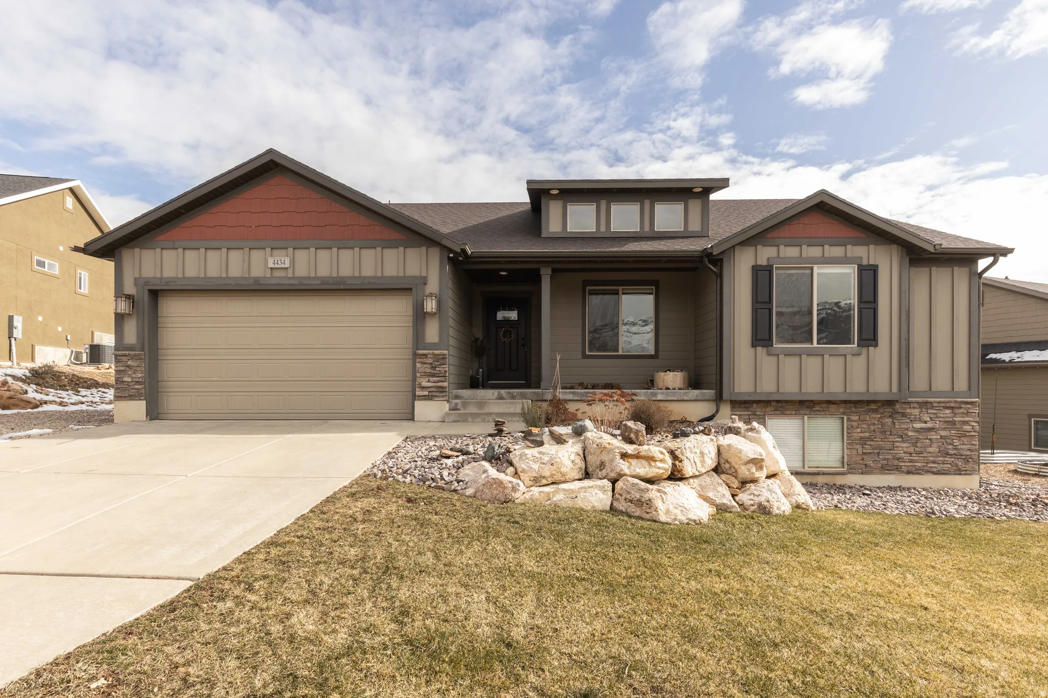 Craftsman house with board and batten siding, a porch, stone siding, and a front lawn