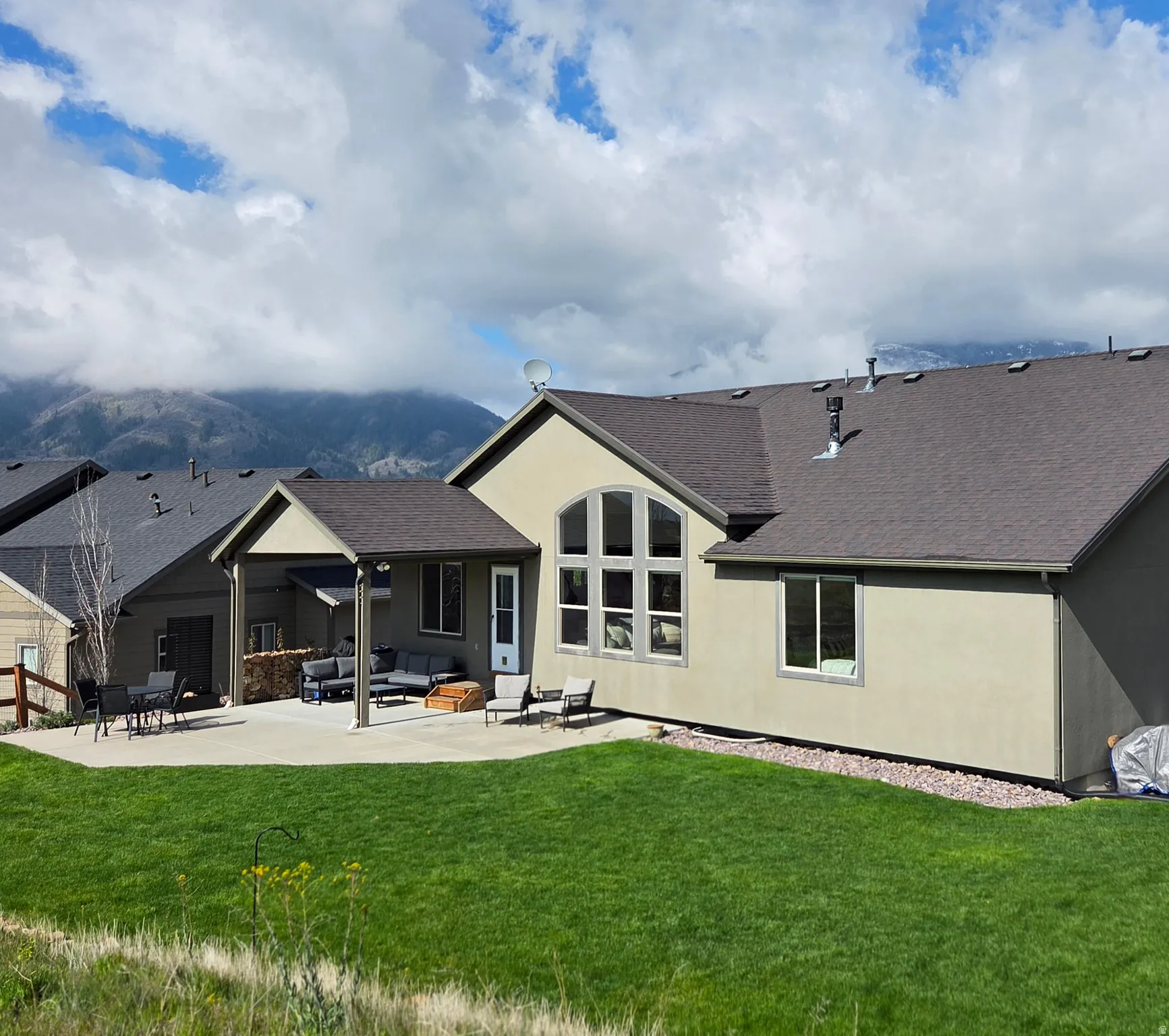 Rear view of property featuring a lawn, a shingled roof, a patio area, outdoor lounge area, and a mountain view
