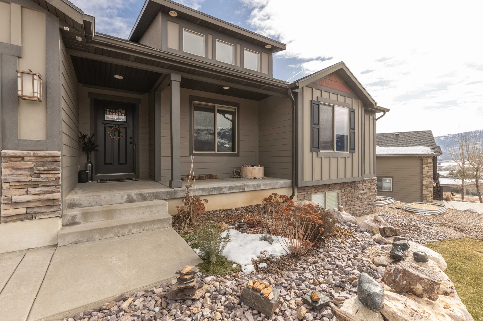 Doorway to property featuring a porch, stone siding, and board and batten siding