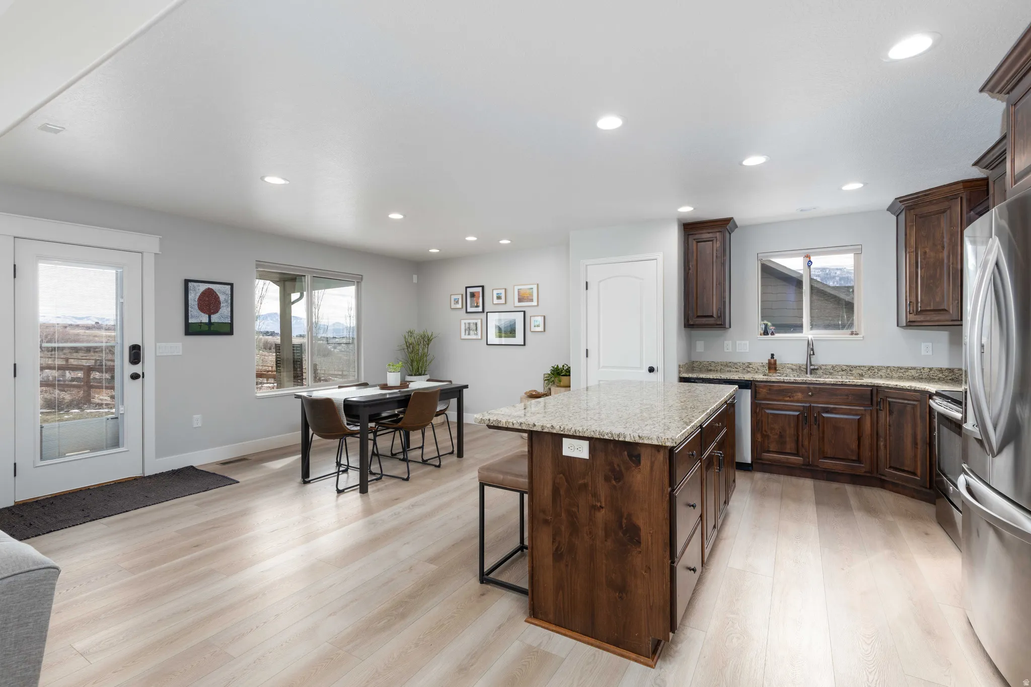 Kitchen featuring a center island, stainless steel appliances, light wood-type flooring, light stone countertops, and recessed lighting