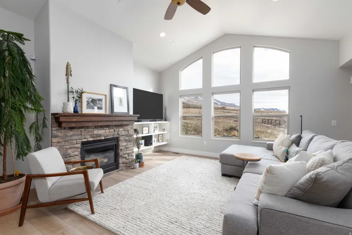 Living room with vaulted ceiling, wood finished floors, a fireplace, ceiling fan, and recessed lighting