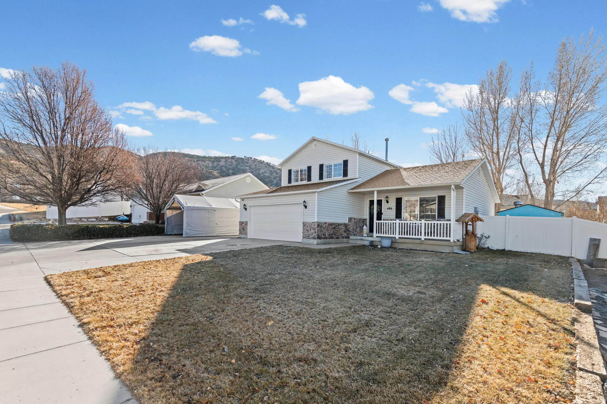 View of front of house with concrete driveway, stone siding, a porch, and a mountain view