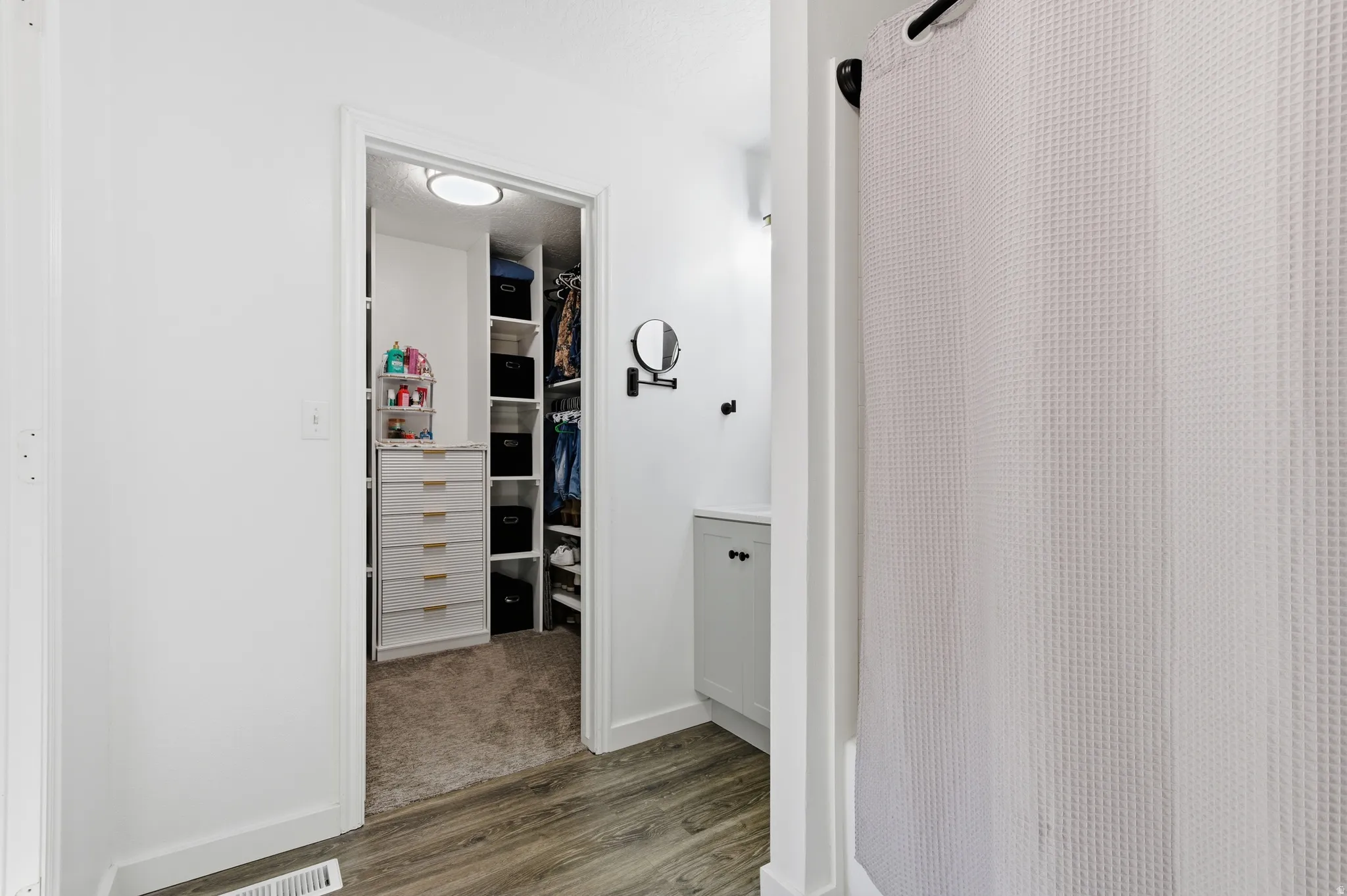 Full bath with dark wood-style flooring, a walk in closet, a textured ceiling, shower / tub combo, and vanity