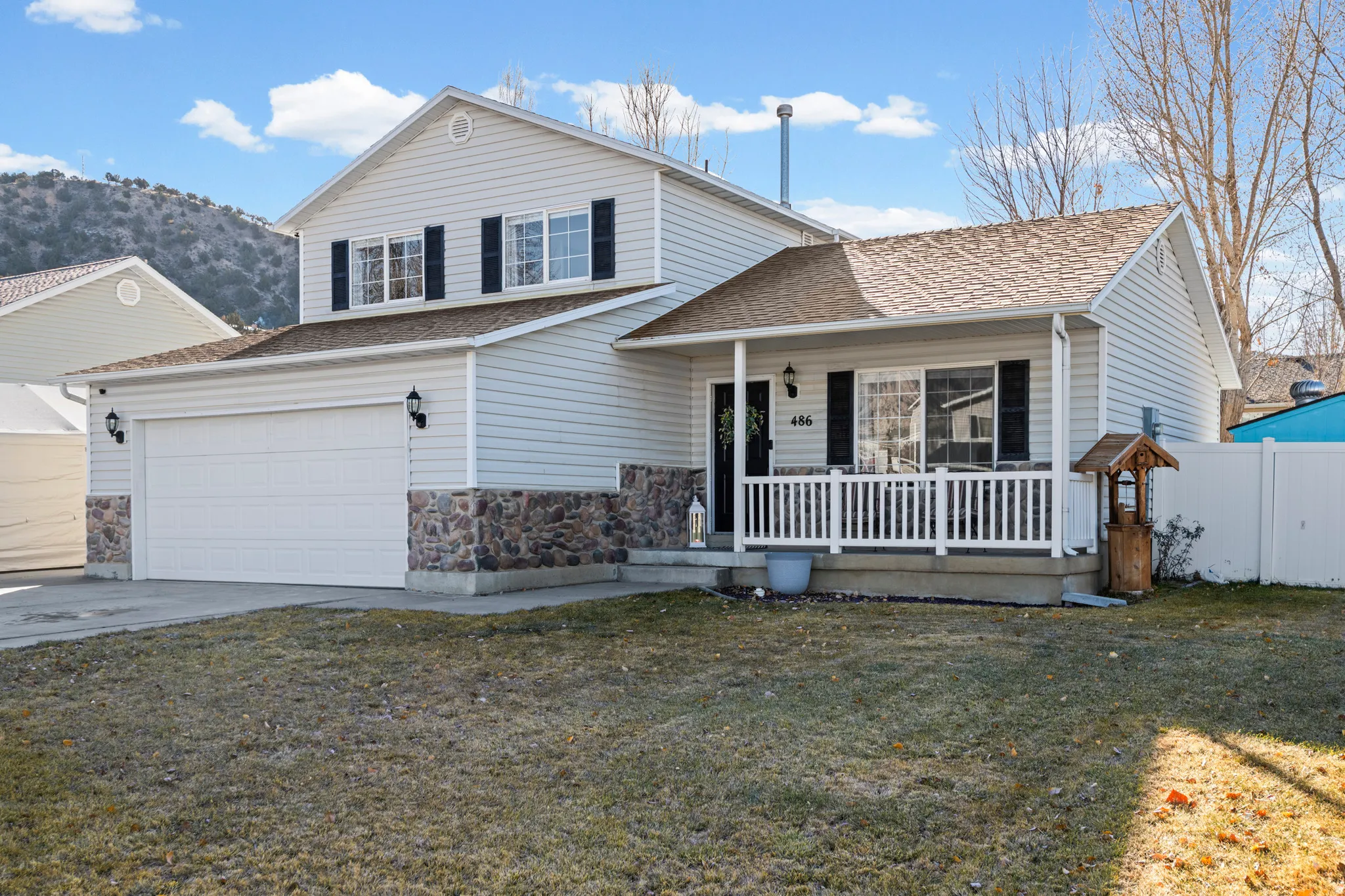 Traditional-style house with covered porch, a garage, concrete driveway, stone siding, and a shingled roof