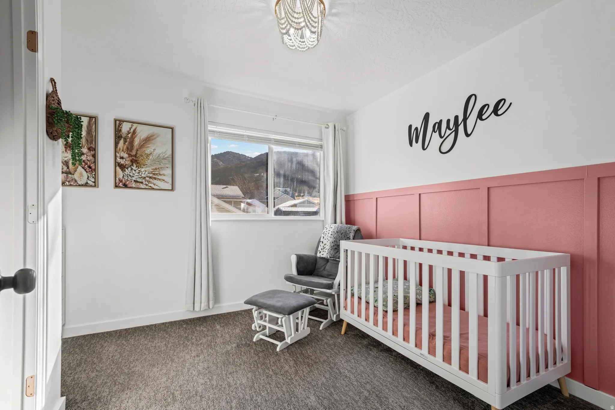 Bedroom with a nursery area, dark colored carpet, a decorative wall, and wainscoting