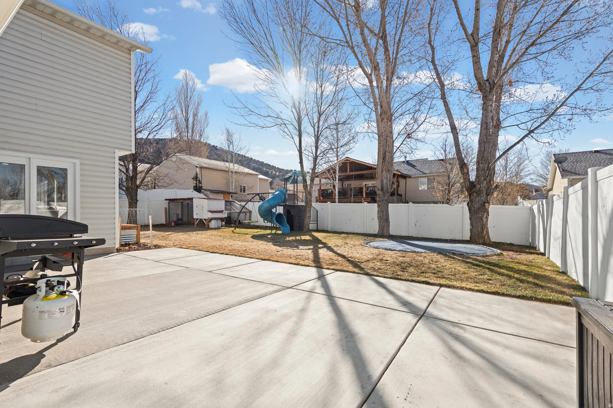Fenced backyard featuring a playground and a patio