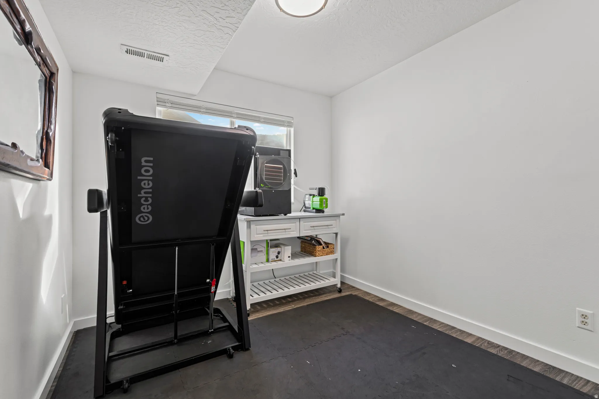 Exercise area with a textured ceiling and baseboards