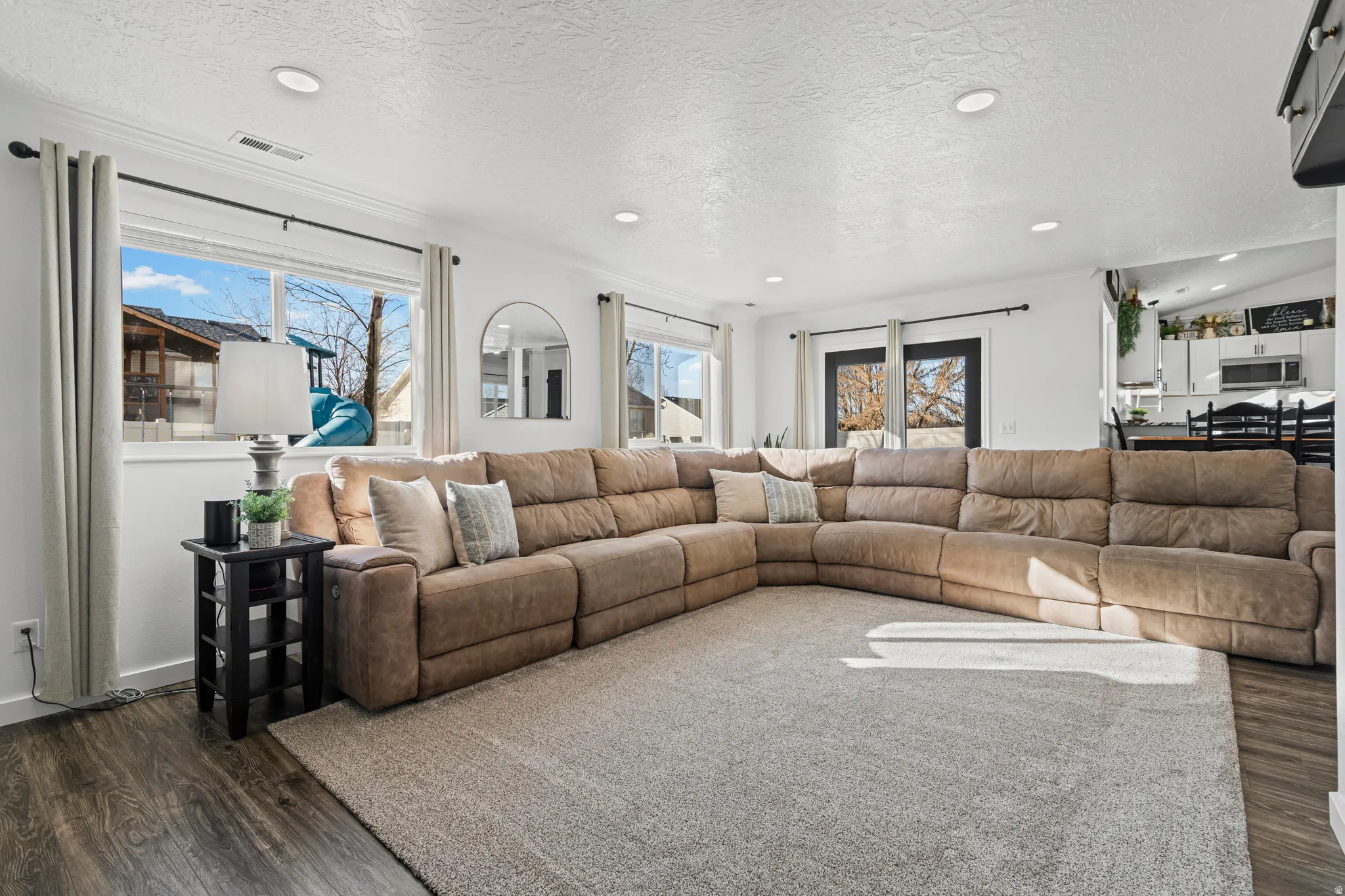Living room featuring a textured ceiling, dark wood-type flooring, and recessed lighting