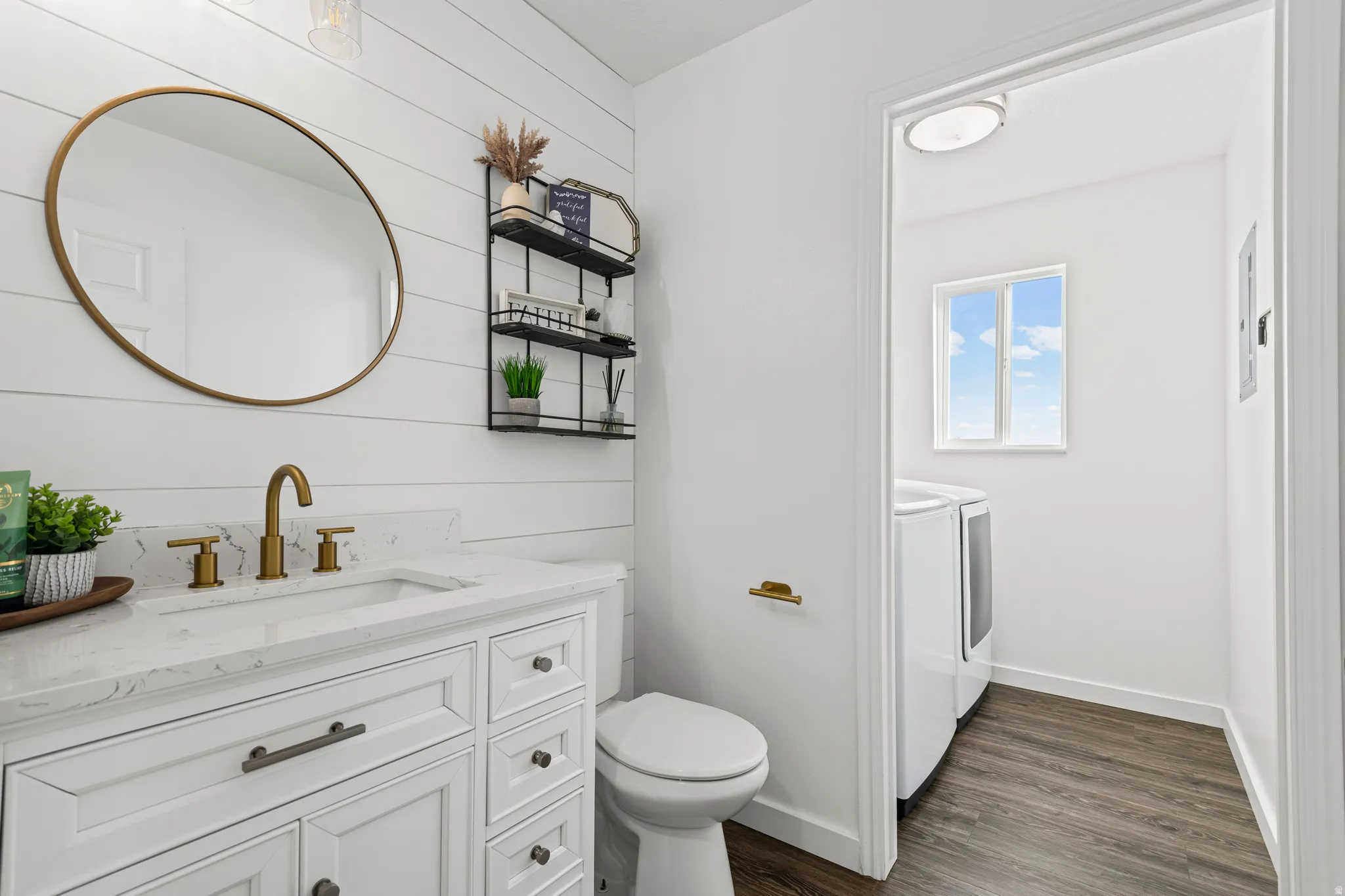Bathroom featuring vanity, washing machine and dryer, dark wood-type flooring, and wooden walls