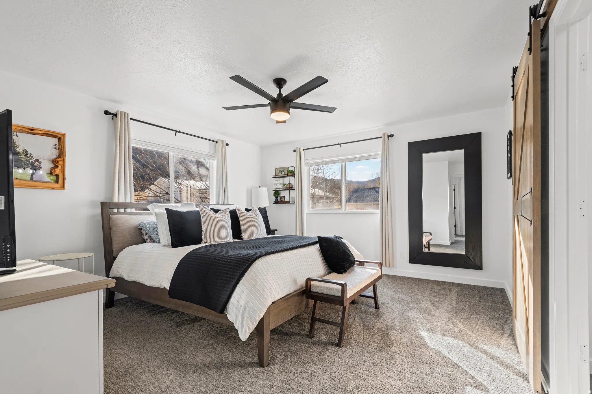 Bedroom with a barn door, light colored carpet, and a ceiling fan