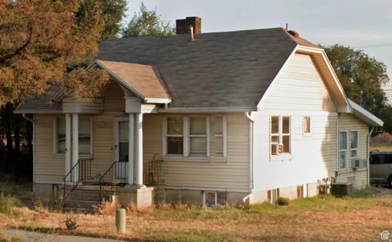 View of front of house featuring a chimney, heating fuel, and roof with shingles