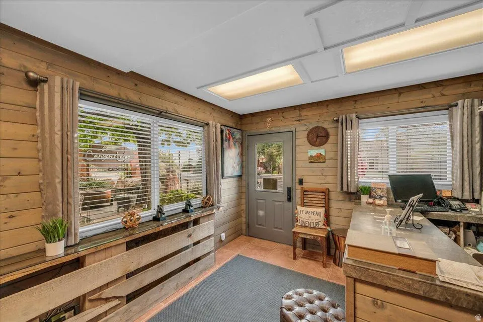 Office featuring wood walls, light tile patterned floors, and healthy amount of natural light