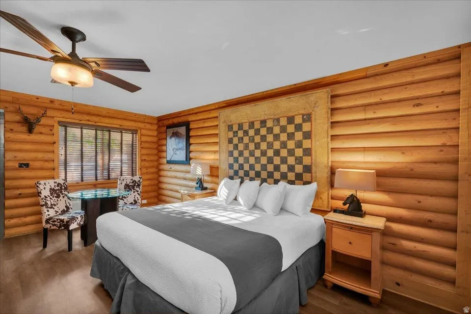 Bedroom featuring log walls, ceiling fan, and wood finished floors