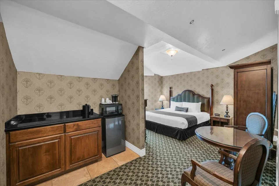 Bedroom featuring wallpapered walls, refrigerator, lofted ceiling, and light tile patterned floors