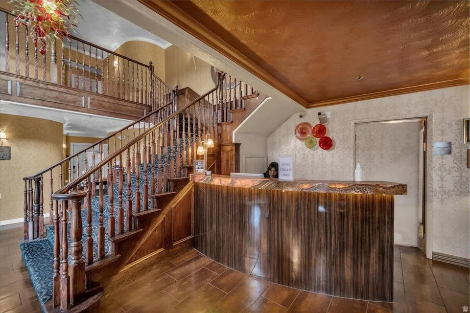 Bar area featuring ornamental molding, wallpapered walls, and dark wood-style flooring