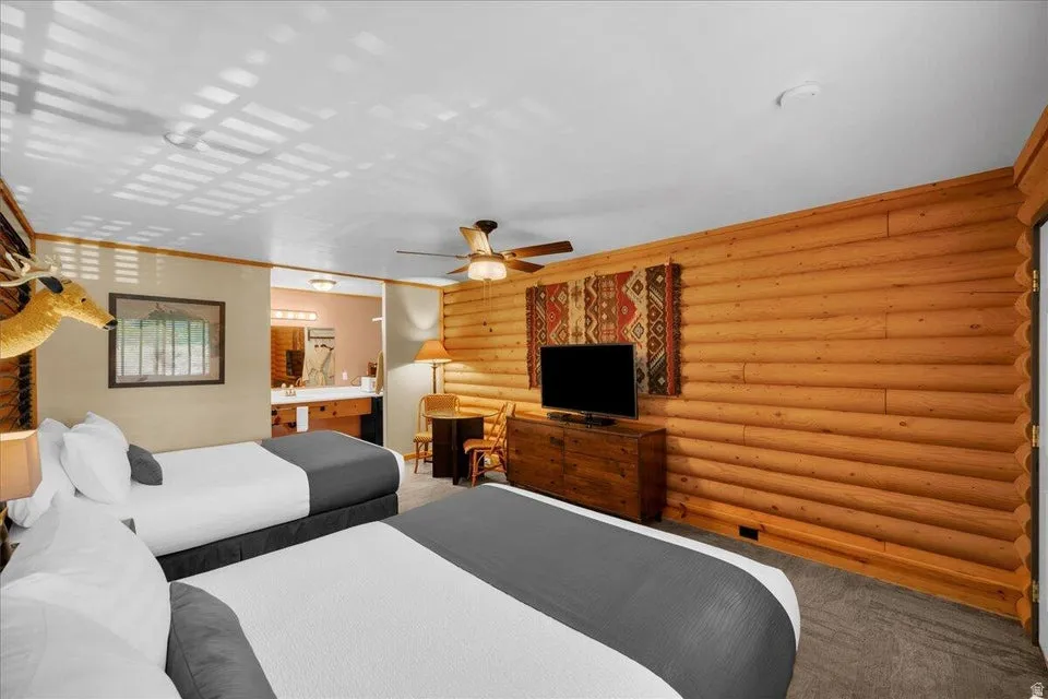 Bedroom featuring carpet, log walls, and connected bathroom