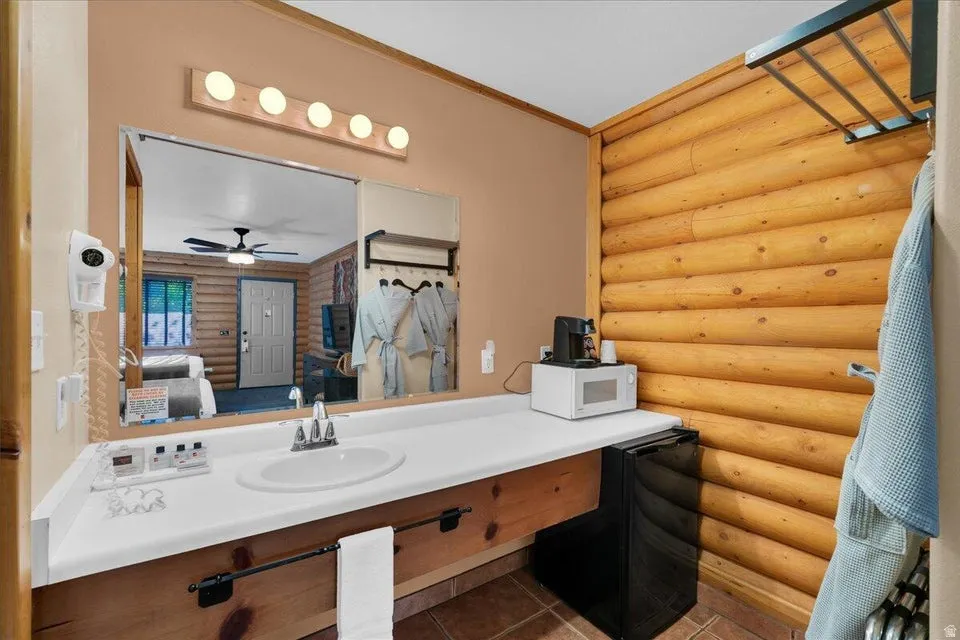 Bathroom featuring log walls, crown molding, vanity, ensuite bathroom, and dark tile patterned floors