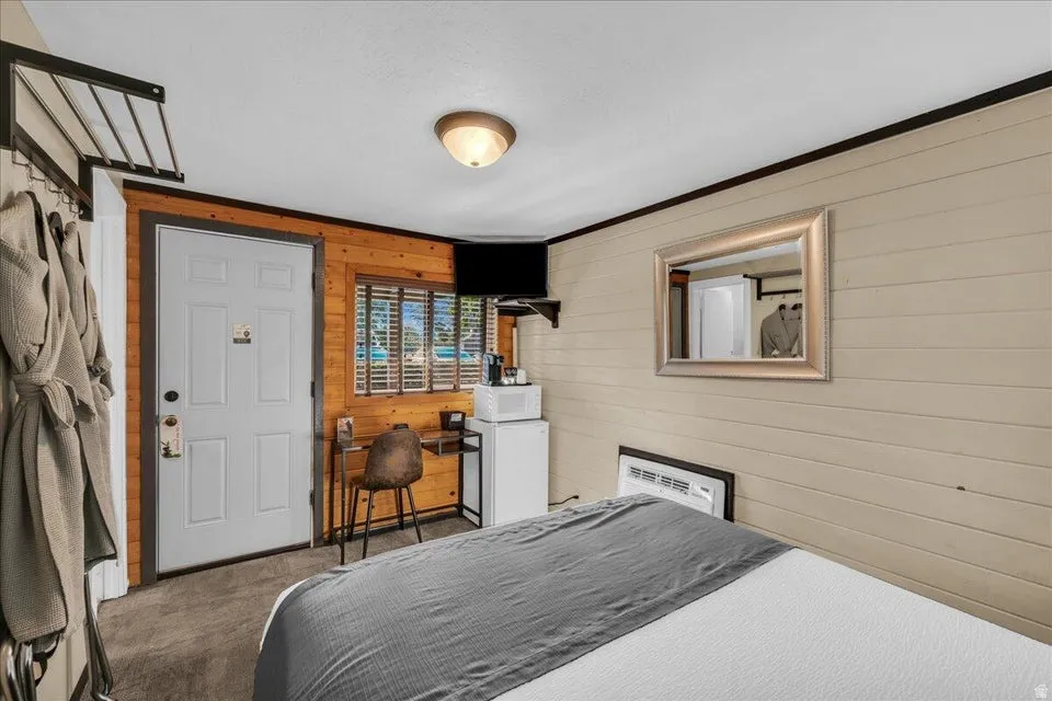 Bedroom featuring wooden walls, carpet flooring, and crown molding