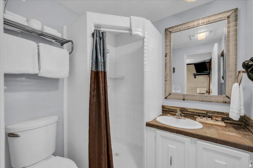 Bathroom featuring vanity, a shower stall, and tasteful backsplash